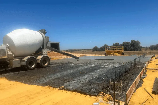An agitator truck pouring concrete into a reinforced slab on a remote site