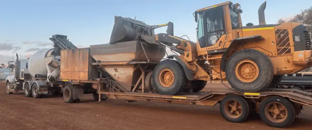 A loader on a float and an agitator truck travelling to a regional job