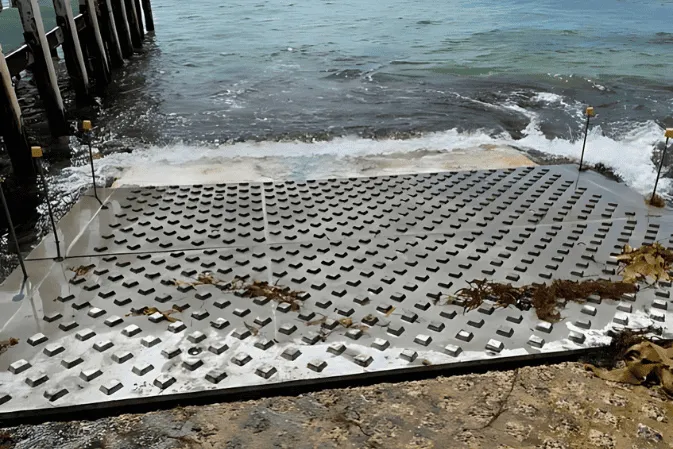 Textured precast boat ramp panels running into the sea beside a jetty