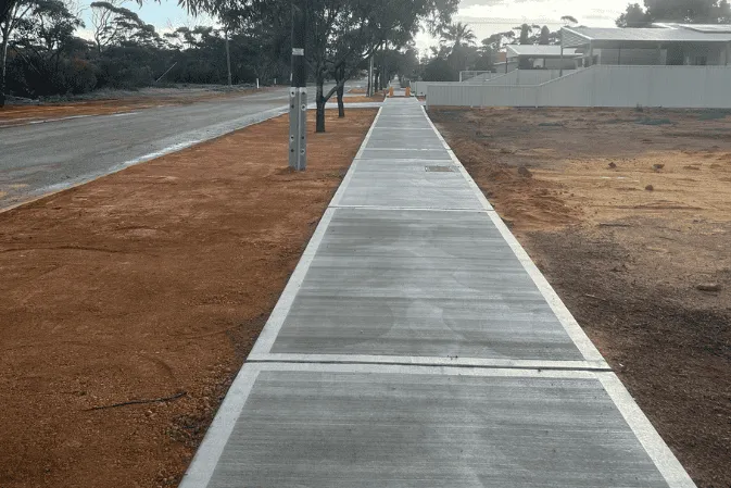 A long new concrete path running between gravel verges