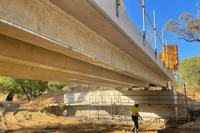 Looking along the underside of precast bridge beams over a creek