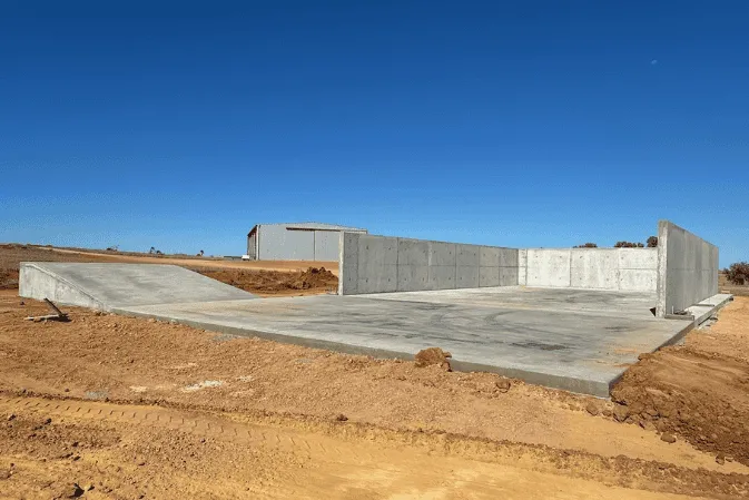 Tilt-panel concrete walls around a new slab on red dirt